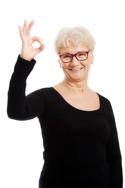 Glad gammal kvinna i glasögon visar ok. — Stockfoto