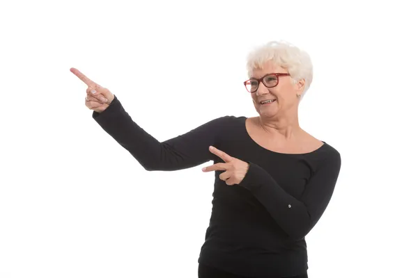 An old happy lady pointing on a copy space. — Stock Photo, Image