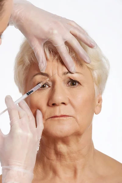 En gammal kvinna med en injektion-skönhet-konceptet. — Stockfoto