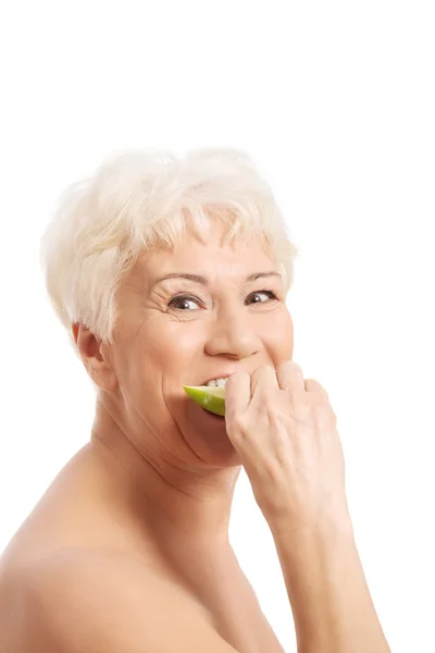Nude old woman eating an apple. — Stock Photo, Image