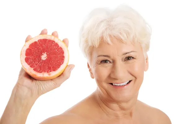 Nude old woman holding a grapefruit. — Stock Photo, Image