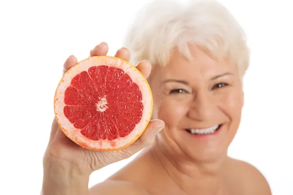 Nackte alte Frau mit einer Grapefruit. — Stockfoto