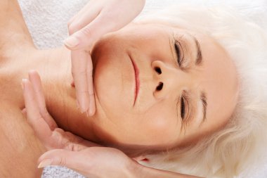 yaşlı bir kadın yüz masaj yapıyor. Spa Konsept.