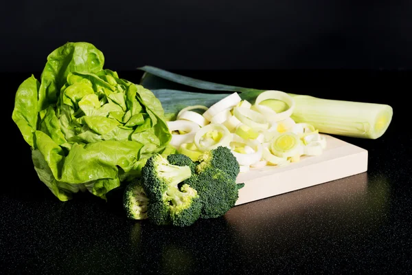 Salat, Brokkoli und Lauch auf Schneidebrett. — Stockfoto