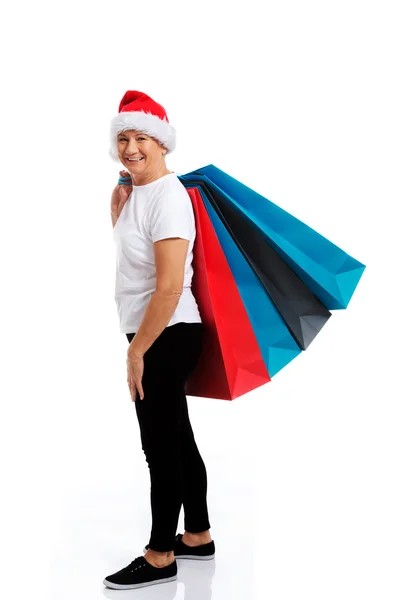 An old woman holding presents,bags in santa hat. — Stock Photo, Image