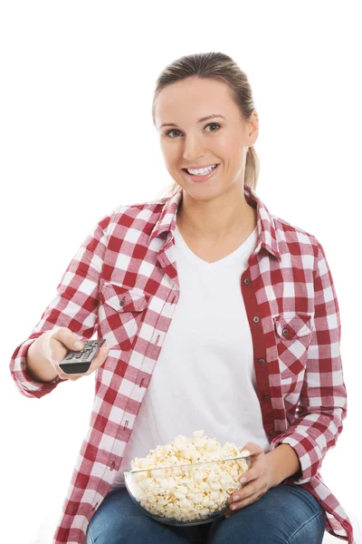 Ung casual kvinna med fjärrkontroll och skål med popcorn. — Stockfoto