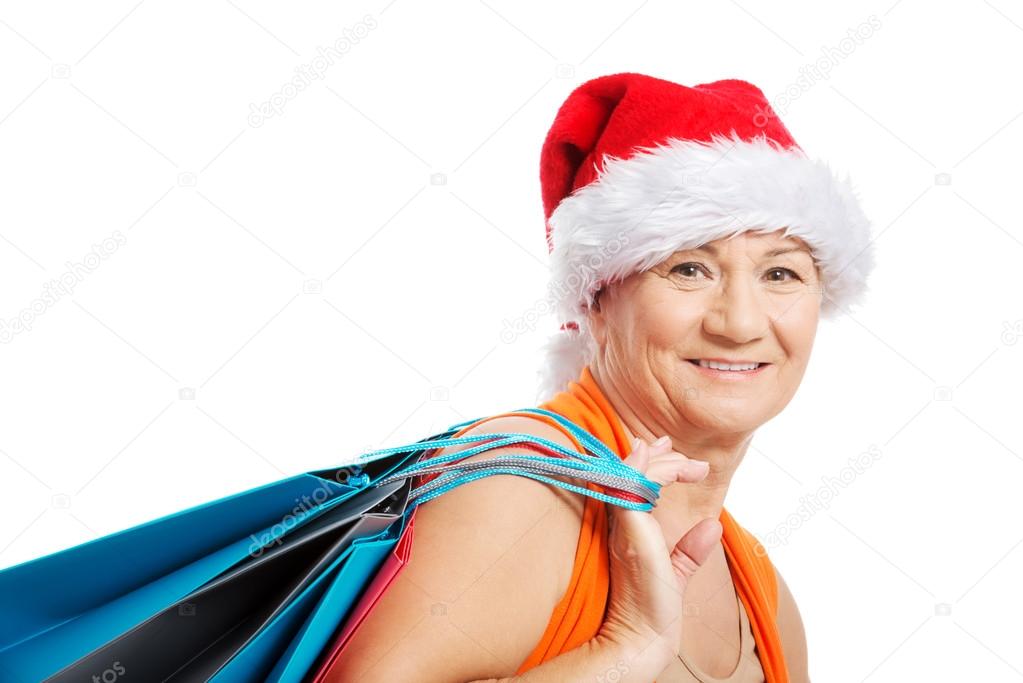 An old woman holding presents,bags in santa hat.