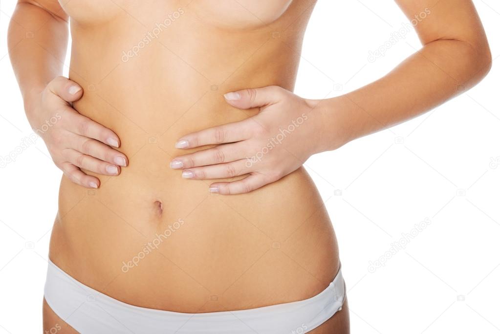 Topless woman's touching her flate belly.