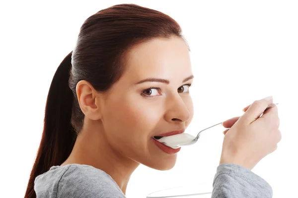 Casual jongedame eten een yoghurt. — Stockfoto