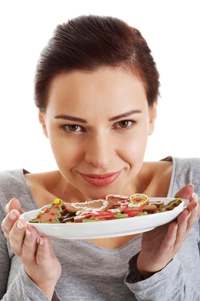 Hermosa joven con galletas en un plato . — Foto de Stock