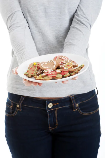 Beautiful young woman with cookies on a plate. — Stock Photo, Image