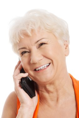 yaşlı bir kadın telefonla konuşuyor.