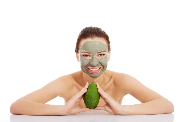 Beautiful woman with facial mask holding avocado. — Stock Photo, Image