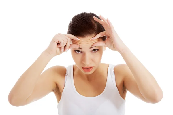 Joven hermosa mujer está comprobando sus arrugas en la frente . — Foto de Stock