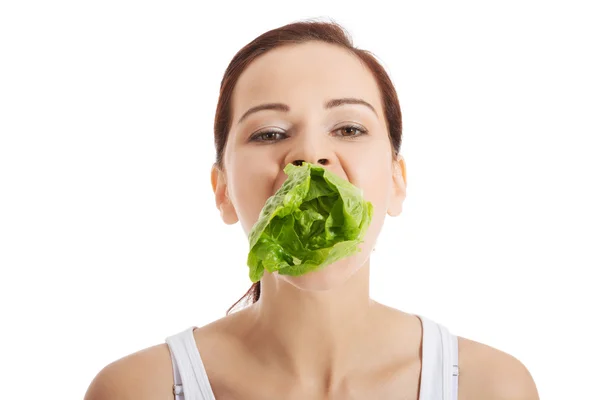 Schöne Frau mit Salatblatt im Mund. — Stockfoto