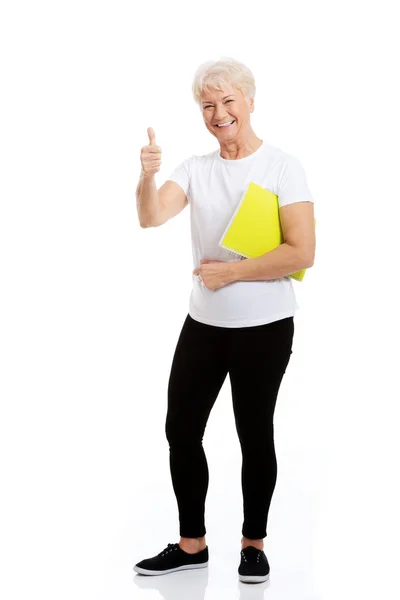 Una vecchia donna che tiene la cartella di lavoro e mostra OK . — Foto Stock