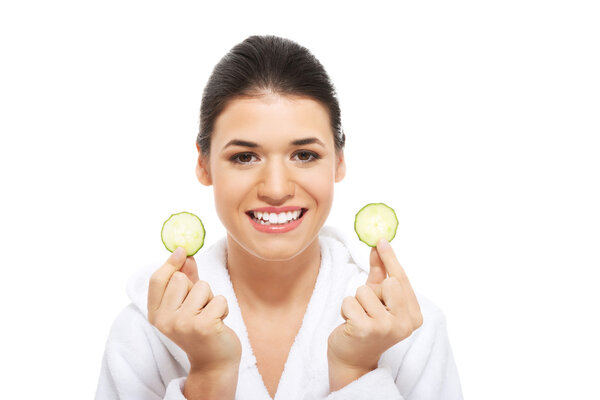 Beautiful woman in bathrobe holding cucumbers.