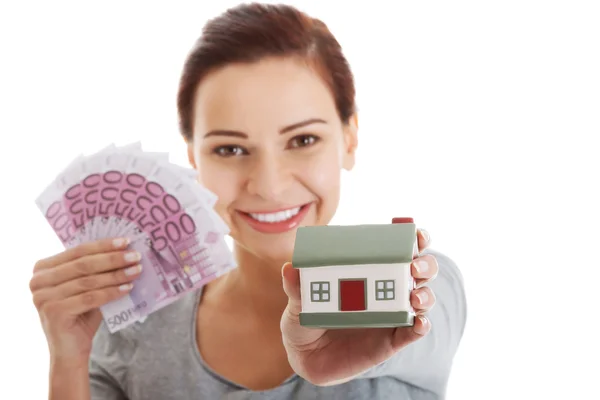 Beautiful young, casual woman holding money and house. — Stock Photo, Image