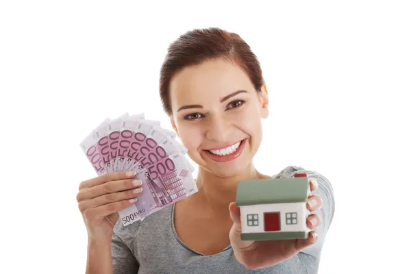Krásná mladá, příležitostné žena drží peníze a dům. — ストック写真