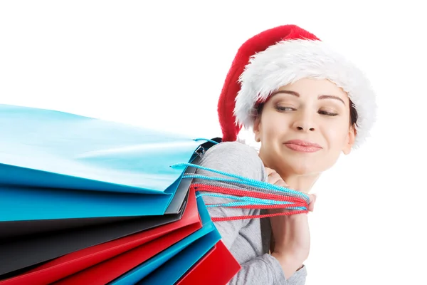 Hermosa mujer en santa hat llevando bolsas de compras . —  Fotos de Stock