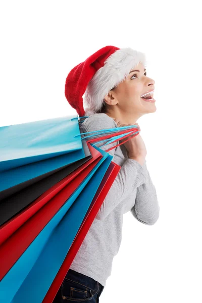 Hermosa mujer en santa hat llevando bolsas de compras . —  Fotos de Stock