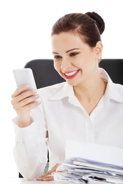 Beautiful business woman sitting by a desk with stack of papers. — Stock Photo, Image