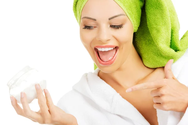 Beautiful woman in bathrobe, turban and holding face cream. — Stock Photo, Image