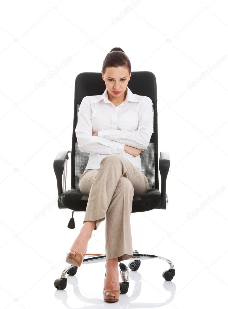 Young sad business woman sitting on a chair.