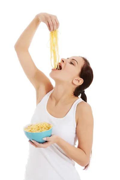 Jovem mulher bonita comendo massa de uma tigela . — Fotografia de Stock