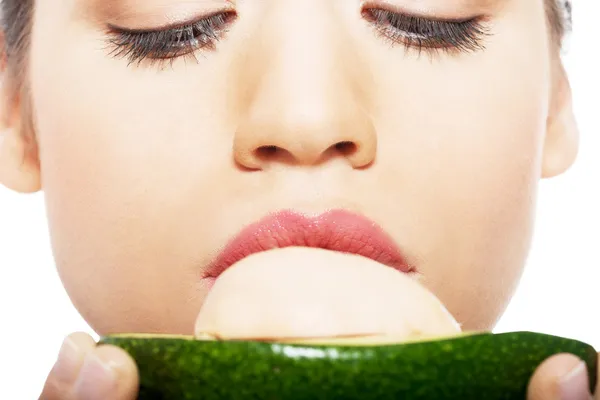 Beautiful woman's face close up and avocado. — Stock Photo, Image