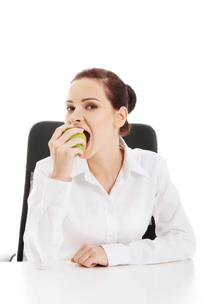 Mooie jonge zakenvrouw eten van een appel. — Stockfoto
