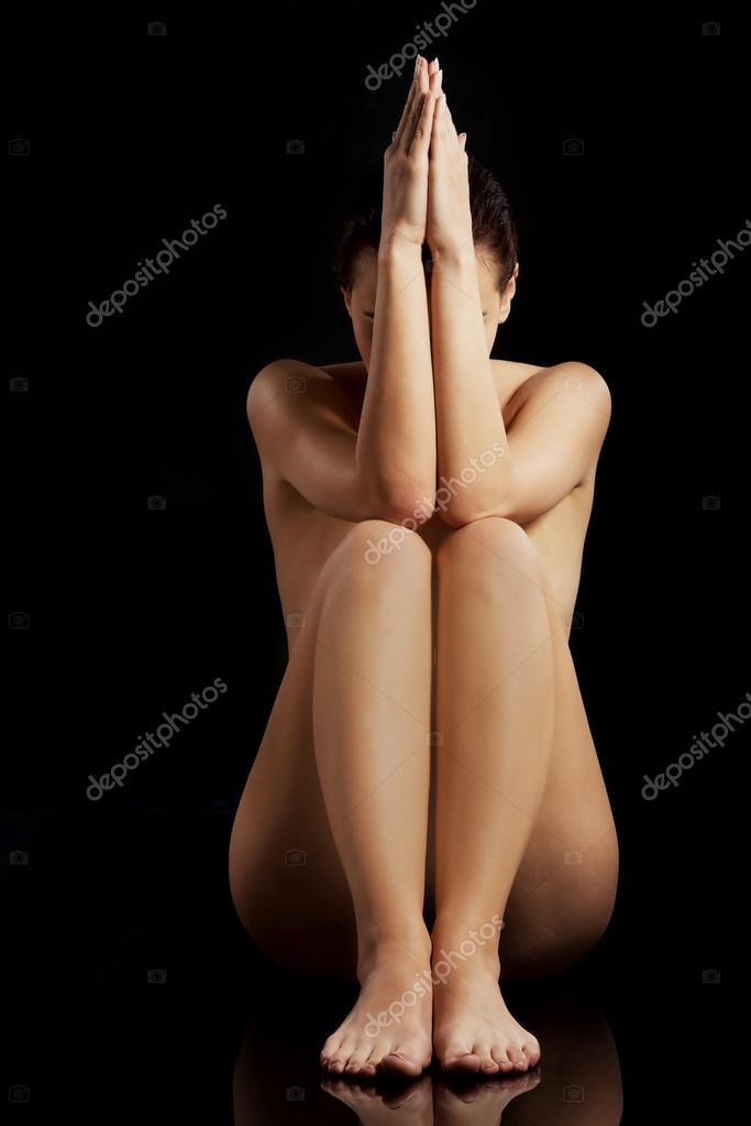 Schöne nackte Frau sitzt mit Hand und Beinen zusammen Stockfoto