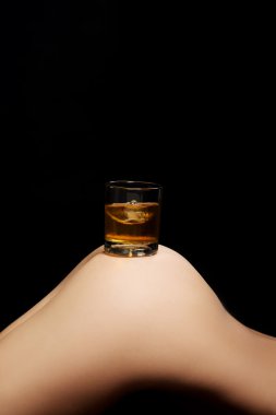 Glass of whisky standing on supple buttock. clipart