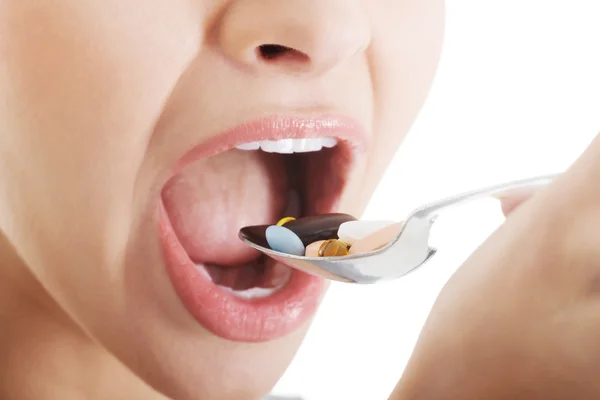 Mujer joven comiendo dosis de píldoras en cuchara . —  Fotos de Stock