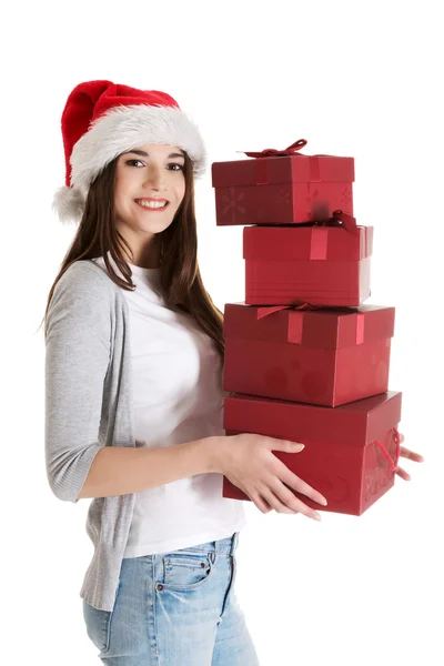 Young beautiful woman in santa hat, holding stock of presents. — Stock Photo, Image