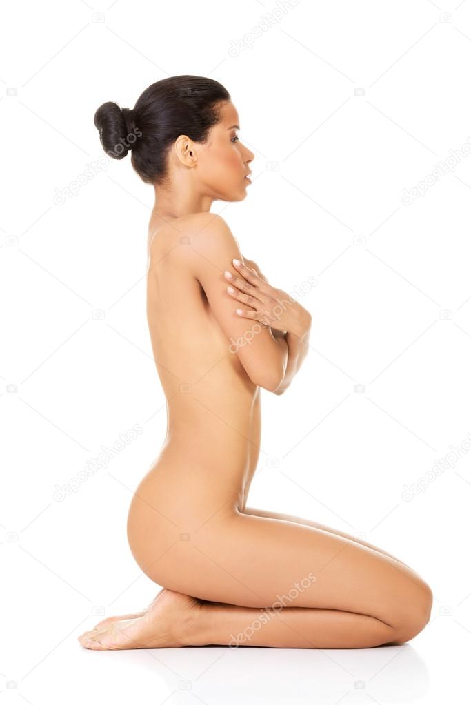 Attractive naked woman sitting on knees. Side view.