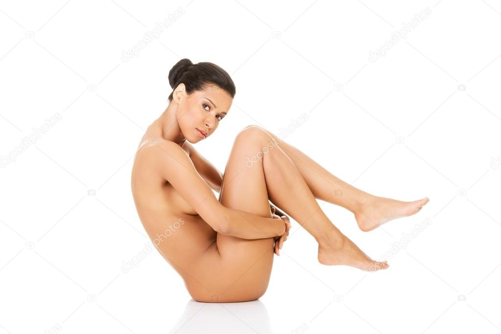 Beautiful naked woman in a crouch, holding her knees.