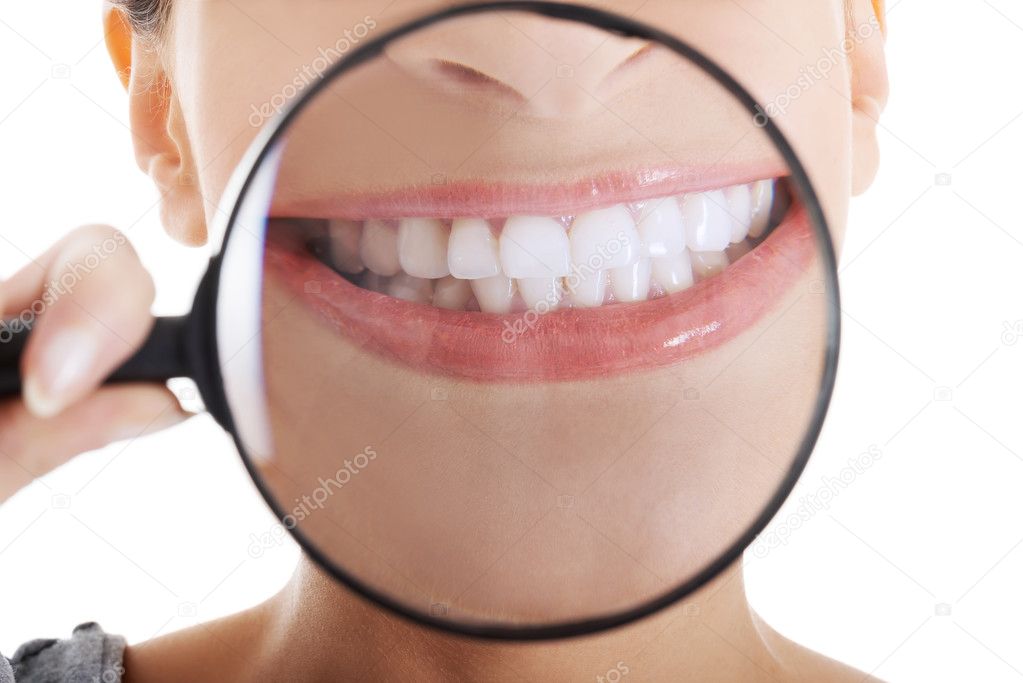 Beautiful woman with magnifying glass showing her perfect white teeth
