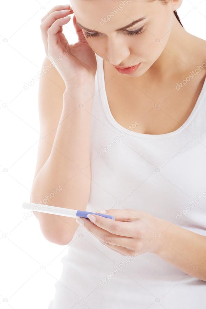 Sad, worried woman holding pregnancy test.