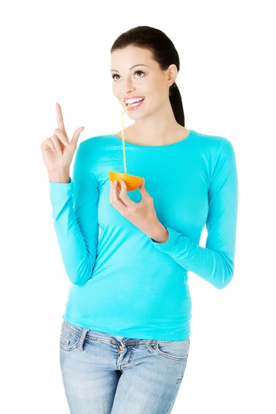 Beautiful young woman drinking juice from orange. — Stock Photo, Image