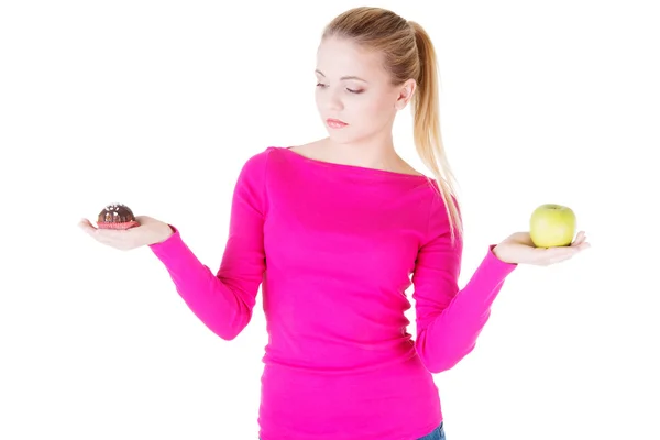 Jeune femme décontractée tenant une pomme et un cookie . — Photo