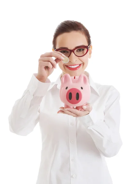 Schöne Geschäftsfrau mit Münze und Sparschwein. — Stockfoto