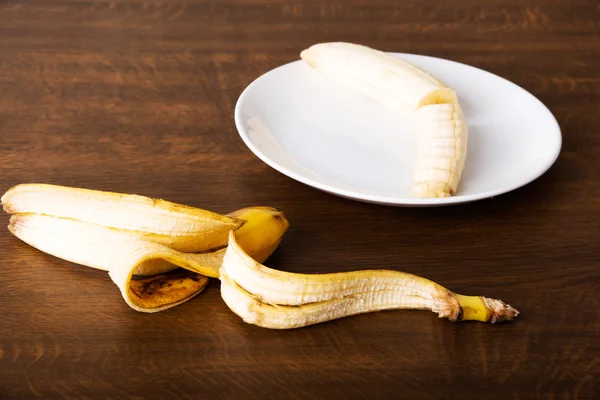 Banana versata su un piatto e la sua pelle sdraiata accanto ad esso . — Foto Stock