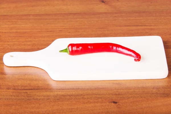 Fresh chili pepper lying on kitchen board. — Stock Photo, Image