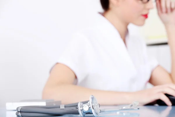 Junge Ärztin sitzt mit Stethoskop. — Stockfoto