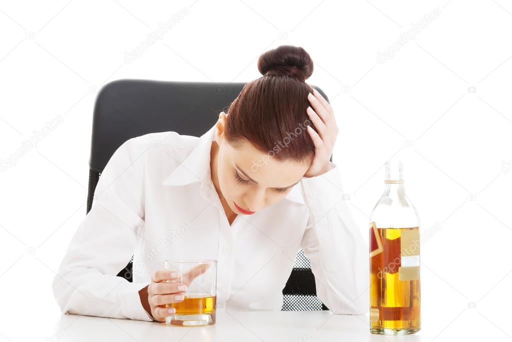 Young beautiful business woman with glass of whisky or rum.