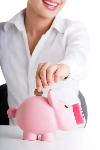 Businesswoman putting a coin into a piggy bank — Stock Photo, Image