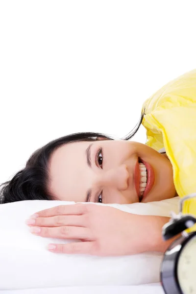 Счастливая молодая женщина лежит в постели и улыбается в камеру — стоковое фото