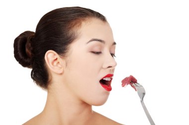 Young beautiful woman eating raw meat.