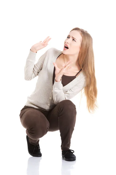 Beautiful casual woman is crouching from sth heavy above her. — Stock Photo, Image